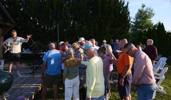 Members of Weston United Methodist Church lay hands on William McQueen and pray for him during a worship service at the pond near Norman Landcraft Sept. 11, 2026.